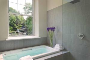 baño con bañera con ventana y jarrón de flores en Ledges Hotel en Hawley