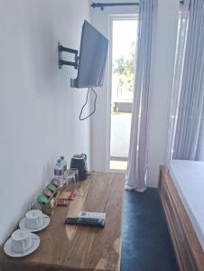 a room with a wooden table with a tv on it at Roman Residence - Unawatuna in Unawatuna