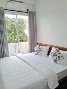 a bedroom with a white bed with pillows and a window at Roman Residence - Unawatuna in Unawatuna