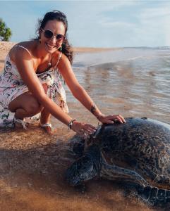 a woman is petting a turtle on the beach at Roman Residence - Unawatuna in Unawatuna