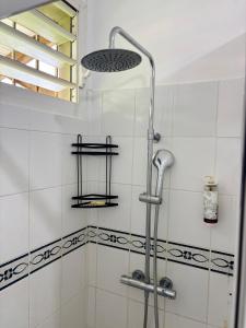 a shower in a bathroom with white tiles at Le nid d'Emijulie - Maison familiale proche plage in Gourbeyre +18 photos