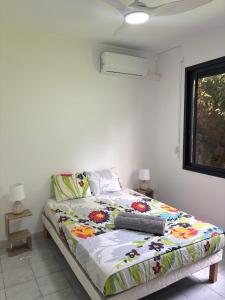 a bedroom with a bed with a colorful comforter at Le nid d'Emijulie - Maison familiale proche plage in Gourbeyre