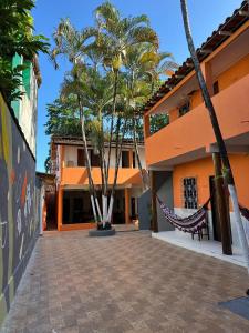 une cour avec des palmiers et un hamac devant un bâtiment dans l'établissement Pousada Flor de Ipê - Arraial d'Ajuda - a 100m da Rua do Mucugê - principal Rua da cidade, à Arraial d'Ajuda