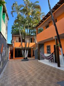 un bâtiment avec des palmiers et un hamac dans une cour dans l'établissement Pousada Flor de Ipê - Arraial d'Ajuda - a 100m da Rua do Mucugê - principal Rua da cidade, à Arraial d'Ajuda 27 autres photos