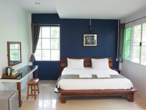 a bedroom with a bed and a blue wall at Muaan Resort in Suphan Buri