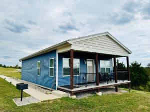 ein blaues Haus mit einer Veranda auf einem Feld in der Unterkunft 100 Acre Relaxing Retreat Near Ark - The Cottage in Williamstown