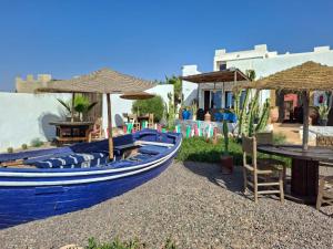 un barco azul junto a una mesa y sombrillas en Riad & Restaurant Ocean Beach Douira, en Agadir