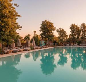 une piscine avec chaises et parasols dans un complexe hôtelier dans l'établissement Waky Club - Designer Flat, à Sraghna