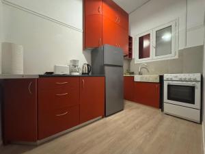 Starfish Airport Apartment في أرتيميدا: مطبخ مع خزائن حمراء وثلاجة