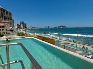 a swimming pool on top of a building next to the beach at Habitacion Frente al Malecon By Partner Host in Mazatlán