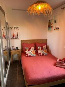 a bedroom with a bed with red sheets and pillows at Vacances en Cévennes in Alès
