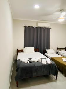 een kamer met twee bedden en een raam bij Mar Suites Tenório in Ubatuba