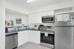 a kitchen with white cabinets and a stainless steel refrigerator at Private Beach and Pool in Gulf Shores