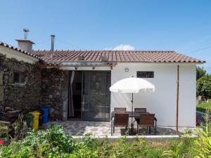 a table and chairs with an umbrella in front of a house at Casa Rosa - Casas Florescer in Fajazinha