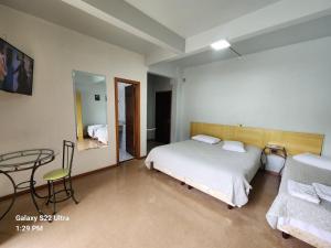 a bedroom with a bed and a table in it at Hotel Vitoria in Videira +1 photo