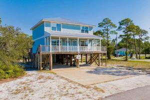 a large blue house on a wooden deck on the beach at Private Beach and Pool in Gulf Shores