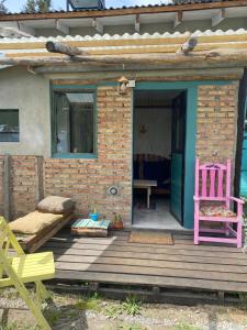 een huis met een roze stoel en een houten veranda bij Lugar bonito tiny house in Lago Puelo