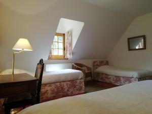 une chambre avec deux lits, un bureau et une fenêtre dans l'établissement charmante longère sur domaine de Kerguéréon, à Ploubezre