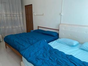 2 camas con sábanas azules en un dormitorio en Comfortable Retreat in Megah Ria, en Masai 2 fotos más