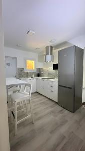 a white kitchen with a table and a refrigerator at Habitación Sant Jeroni en Casa Camí de les Aigües Monistrol de Montserrat in Monistrol