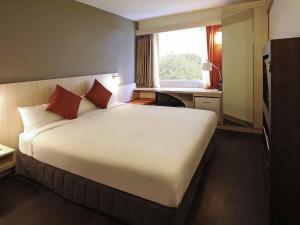 a hotel room with a large bed and a window at ibis Auckland Ellerslie in Auckland