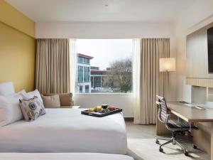 a hotel room with a large bed and a desk at Novotel Auckland Ellerslie in Auckland