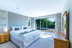 ein Schlafzimmer mit einem großen Bett und einem großen Fenster in der Unterkunft Wanaka Haven Spa Views and fantastic outdoor living in Wanaka