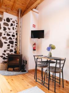 een kamer met een tafel en stoelen en een open haard bij Casa Flor - Flower home in Fajazinha