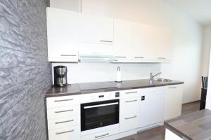 a white kitchen with white cabinets and a sink at Convenient Apartment for 2 with Sauna in Pori