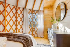 a bedroom with a bed and a mirror and a window at Sunrise Sanctuary -Modern Yurt in Brookville