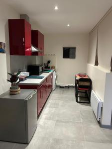 a large kitchen with red cabinets and a counter at Grand studio refait à neuf in Vierzon