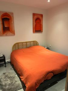 a bedroom with an orange bed with two pictures on the wall at Grand studio refait à neuf in Vierzon