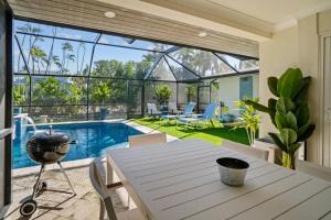 Un comedor con mesa y una piscina. en Islandy, en Sanibel