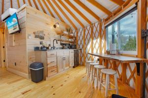 a kitchen in a wooden cabin with a table and stools at Horizon Hideout - Modern Yurt in Brookville