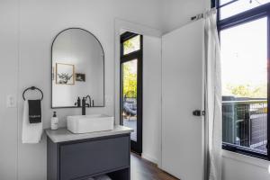 een badkamer met een wastafel, een spiegel en een raam bij Twilight Haven - Hot Tub in Shippenville