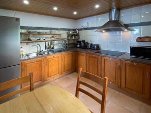 - une cuisine avec des placards en bois, une table et un évier dans l'établissement Casa Cachalote - Ferienhaus auf den Azoren, à São Caetano