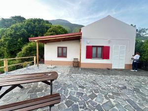 a person standing in front of a house with a bench at Casa Cachalote - Ferienhaus auf den Azoren in São Caetano