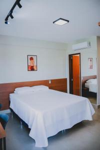 a bedroom with a large white bed with a white blanket at Loft completo e climatizado a 2 minutos do centro in Cuiabá