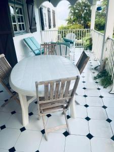 - une table et des chaises blanches sur une terrasse couverte dans l'établissement Appartement spacieux à Rivière-Salée de 180 m², à Rivière-Salée