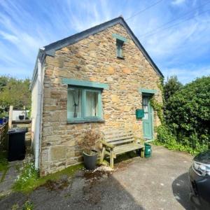 ein Steinhaus mit einer Bank davor in der Unterkunft Bramble Cottage in Saint Columb Minor + 5 Fotos