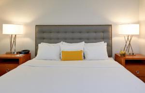 a bedroom with a large bed with a yellow pillow at The Kensington Hotel in Ann Arbor