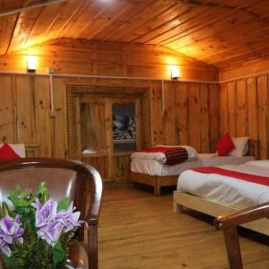 a bedroom with two beds in a wooden cabin at Kalinchowk Tripura Resort in Dhulikhel