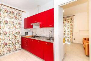 a red kitchen with a sink and red cabinets at Villa tranquilla immersa nel verde a 2 Km dal mare in Chiavari