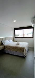a bedroom with a bed and a large window at Apartamento Novinho na Praia de Palmas em Gov Celso Ramos in Governador Celso Ramos