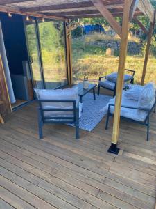 eine Terrasse mit zwei Stühlen und einem Tisch auf einem Deck in der Unterkunft Le nid de l Eyrieux in Saint-Martin-de-Valamas