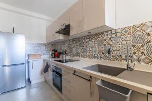cocina con armarios blancos, fregadero y nevera en Villa with garden & great view, Agadir Anza Blue, en Agadir