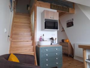 a room with a staircase with a microwave and a blue dresser at L'ANEDA Vue sur mer - COCCONING 2 Personnes - 3ème étage in Mers-les-Bains