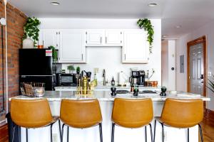 Una cocina con gabinetes blancos y taburetes de bar naranjas. en Prime Location Top Rated Clean Parking Free!, en Columbus