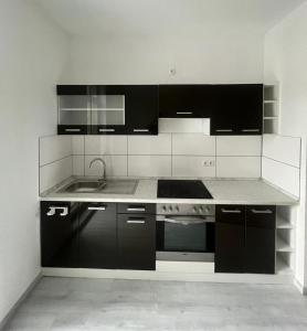 une cuisine avec des armoires noires et blanches et un évier dans l'établissement 5 Personen Apartment mit Badezimmer und Küche, à Niederdorla