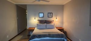 a bedroom with a bed with two tables and a ceiling fan at 7 Vallen Lodge in Ballito